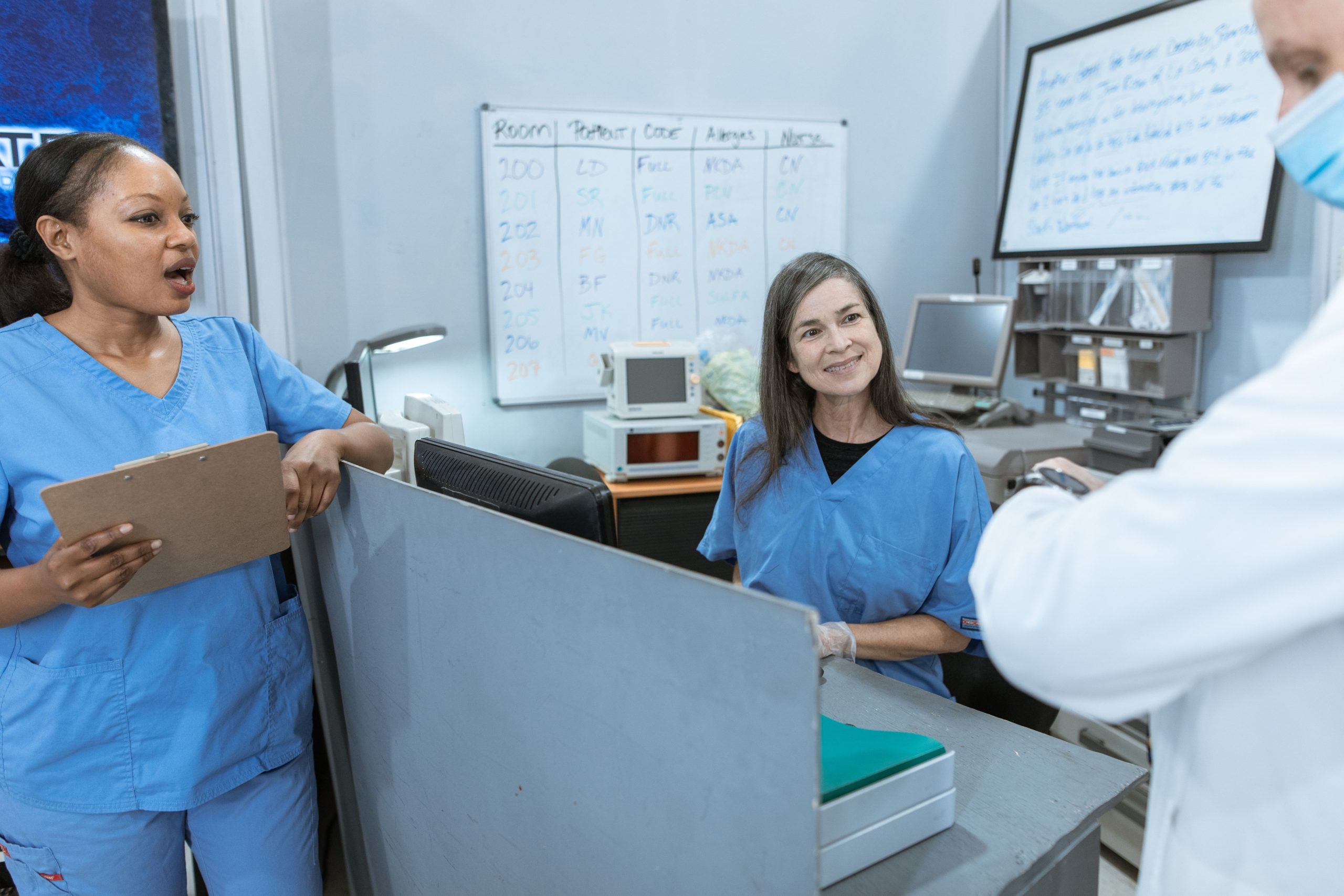 Group of nurses and a doctor collaborating at a hospital reception area with medical equipment in view.